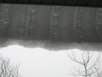 Incredible snow curl hanging off of the covered porch roof